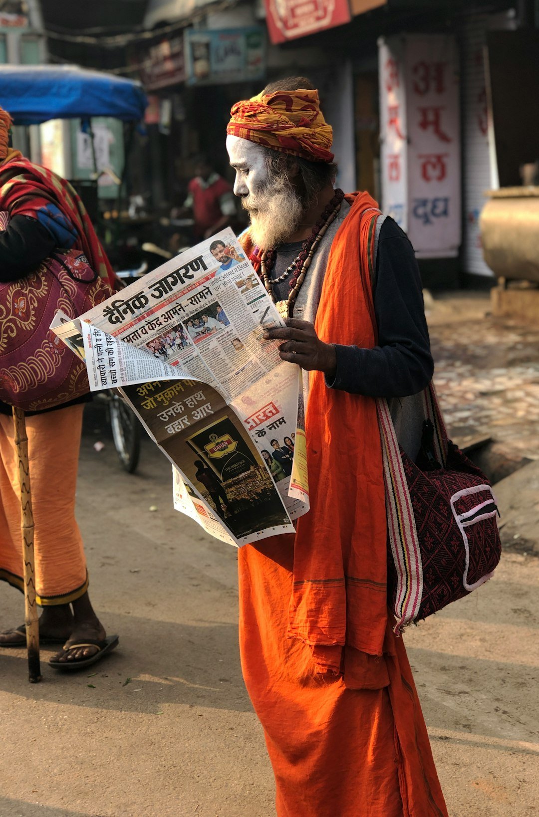 man reading newspaper beside street